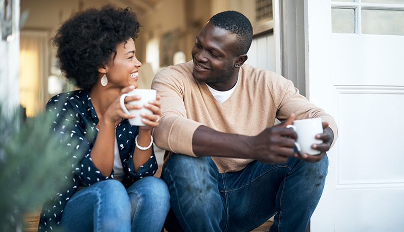 Happy couple having coffee sitting on the steps of their porch | Alliant Private Client