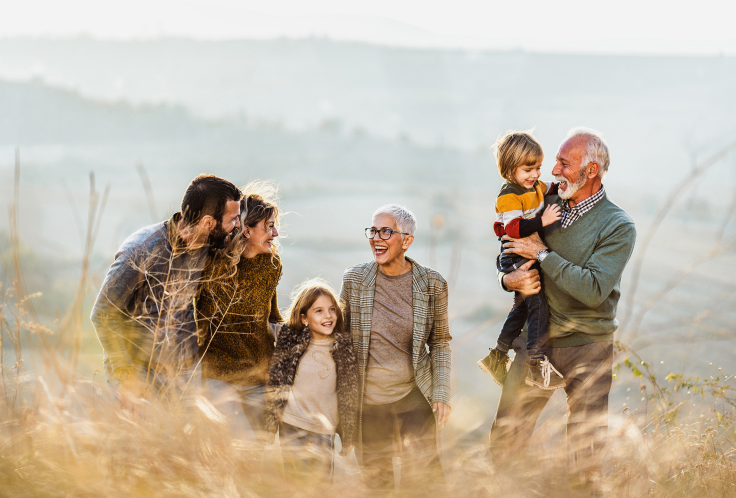 Multi-generational family walking together in field