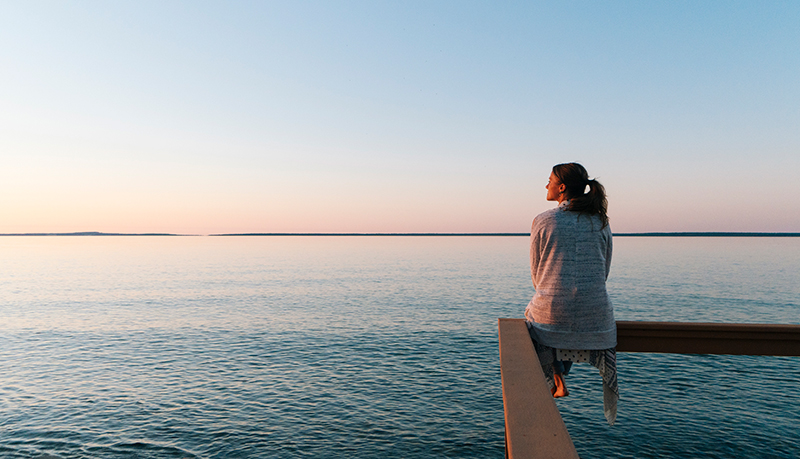 Woman looking pensive out over the ocean | Alliant Private Client