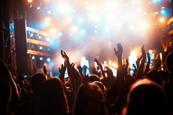 Hands in the air with concert stage in background | Alliant Private Client