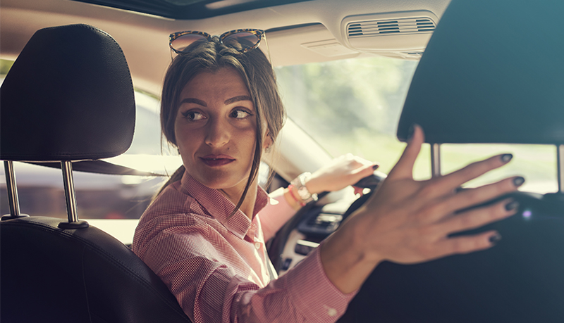 Woman looking over her shoulder as she backs up in car | Alliant Private Client