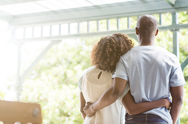 Couple with arms around each other looking out from their porch | Alliant Private Client