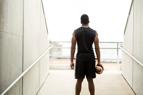 Athlete holding football looking out into stadium | Alliant Private Client