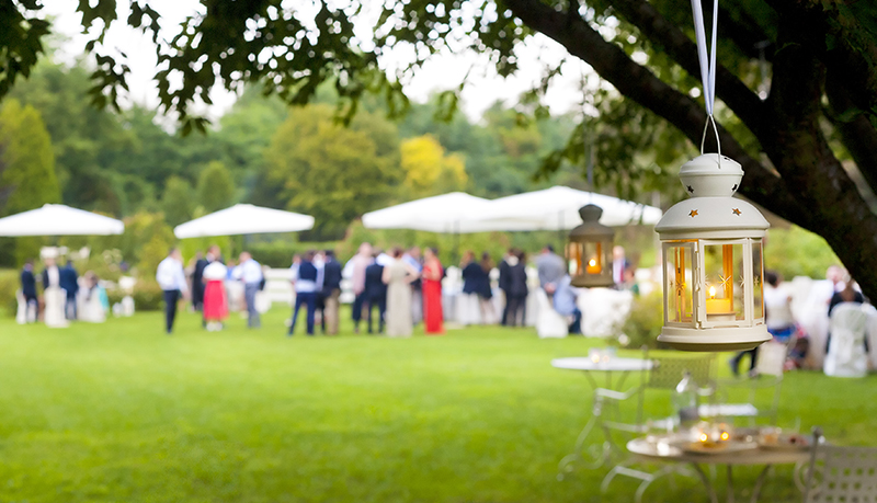 Close up lanterns with guests enjoying outdoor party in distance | Alliant Private Client