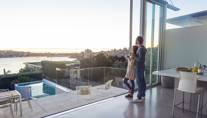 Couple gazing out large sliding glass door at harbor | Alliant Private Client